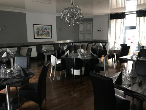 a dining room with tables and chairs and a chandelier at Hotel du Centre in Gueugnon