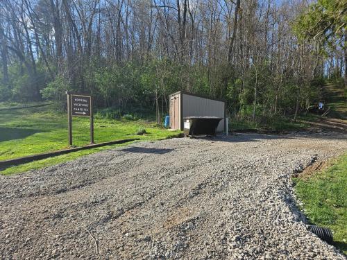 a dirt road with a sign next to a shed at Black Oak Campsite at Hocking Vacations Campsites - Tent not Included in Logan
