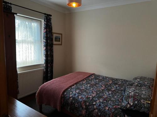 a bedroom with a bed and a window at Celyn Bach Llangrannog in Llwyn-Dafydd