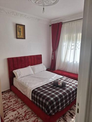 um quarto com uma cama com uma cabeceira vermelha e uma janela em Votre chez-vous à Agadir em Agadir