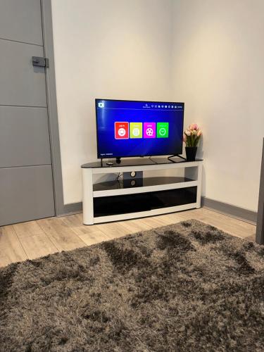 a flat screen tv sitting on a tv stand in a living room at Modern studio flat in Romford in Havering atte Bower