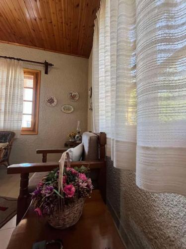 a living room with a chair and a basket of flowers at Rustic and Spacious House in Mytilinioí