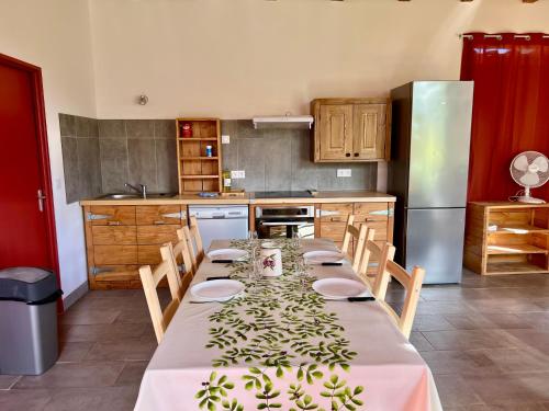 a kitchen with a long table with chairs and a refrigerator at L'atelier du Salagou in Octon
