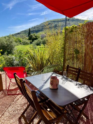 a table with wine glasses and a red umbrella at L'atelier du Salagou in Octon