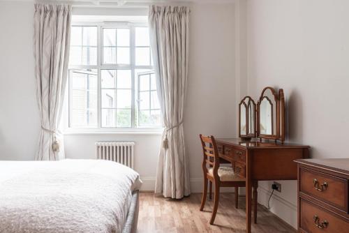 Schlafzimmer mit einem Schreibtisch, einem Bett und einem Fenster in der Unterkunft Chestnut Blossom - 1 Bedroom in Kensington in London