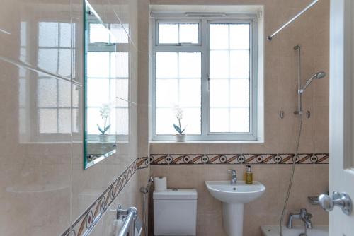 a bathroom with a sink and a toilet and a window at Chestnut Blossom - 1 Bedroom in Kensington in London