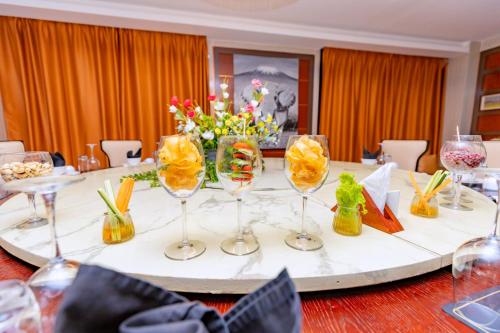 a table with wine glasses and flowers on it at M Hotel Kigali in Kigali