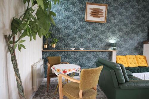 a living room with a table and a green couch at Gîte La Vigne Verte in Saint-Sigismond