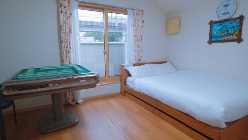 a bedroom with a bed and a table and a window at 東賀旅館 in Tokyo