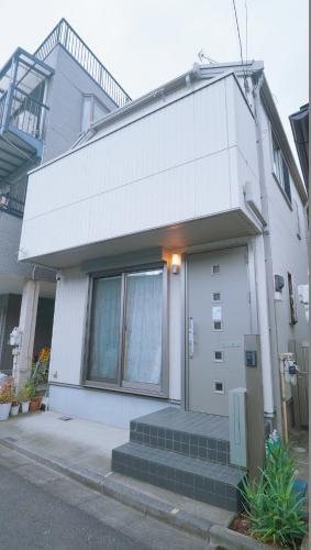 a white house with a door and stairs in front of it at 東賀旅館 in Tokyo