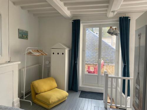 une chaise jaune dans une chambre avec fenêtre dans l'établissement La Crabette Bleue, à Grandcamp-Maisy