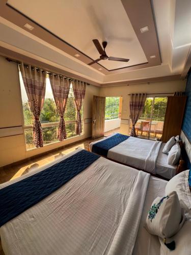 two beds in a room with two windows at The Midway Jungle Resort in Masinagudi
