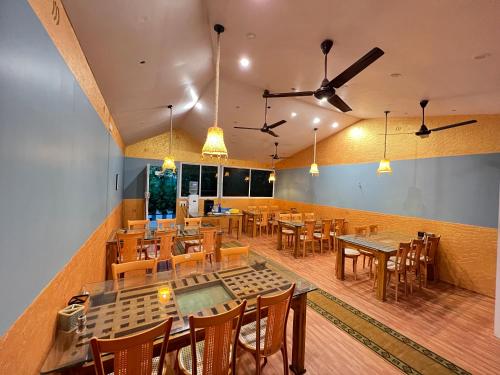 een restaurant met houten tafels en stoelen en plafondventilatoren bij The Midway Jungle Resort in Masinagudi