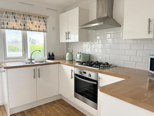 a kitchen with white cabinets and a stove top oven at Hot Tub With A View - Christchurch Harbour in Christchurch