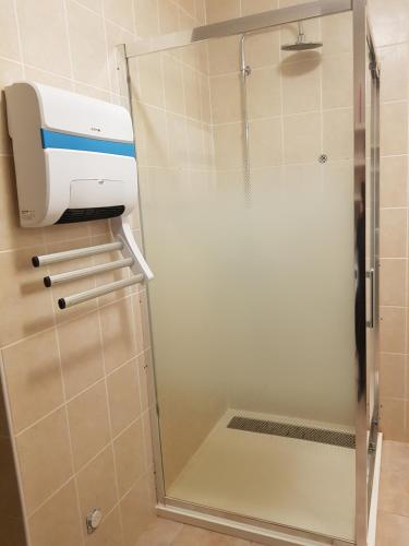 a glass shower door in a bathroom with a hair dryer at Maison au calme in Castillon-du-Gard