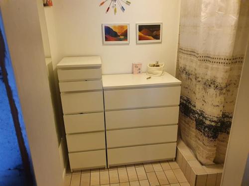 La salle de bains est pourvue de tiroirs blancs et d'une douche. dans l'établissement Apartment with a panoramic view, à Viðareiði