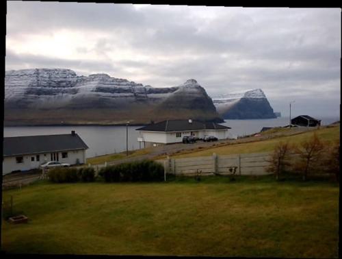 a house in a field next to a body of water at Apartment with a panoramic view A in Viðareiði