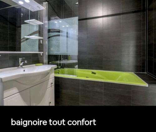 une salle de bain avec une baignoire verte et un lavabo dans l'établissement Terrasse Vieux Port (CLIM), à Marseille