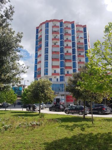 a tall building with a parking lot in front of it at Prime Luxury Apartments in Lushnjë