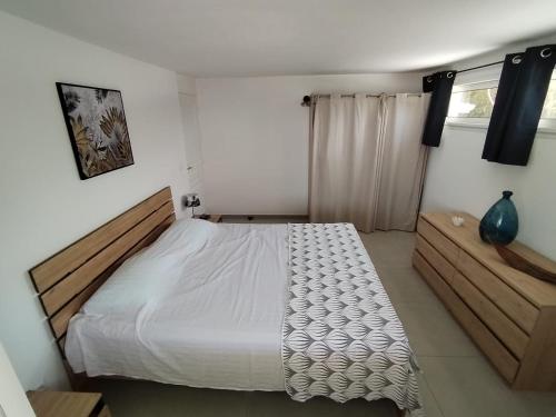 a bedroom with a white bed and a window at Résidence La Palmeraie in Le Diamant