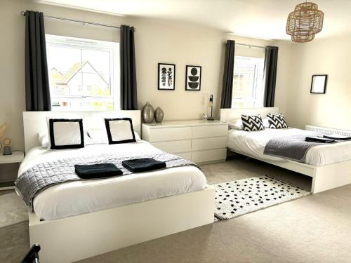 a white bedroom with two beds and a window at Stansted Coach House in Elsenham