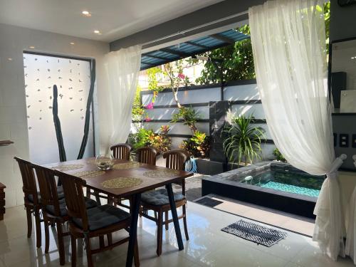 a dining room with a table and chairs and a swimming pool at Deja View in Jimbaran