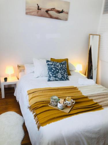 Una cama con una bandeja con dos tazas. en Quarto Duplo em Lisboa - Casa de Anfitrião en Lisboa