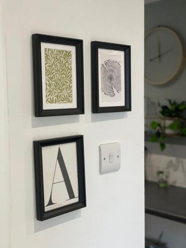 three framed pictures hanging on a wall with a clock at Cosy home close to M6 motorway in Pemberton