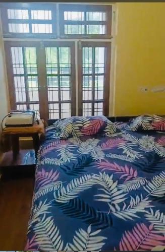 a bed with a blue comforter in a room with windows at Pretty park facing 2 bedroom guesthouse near lohia park Gomtinagar in Lucknow