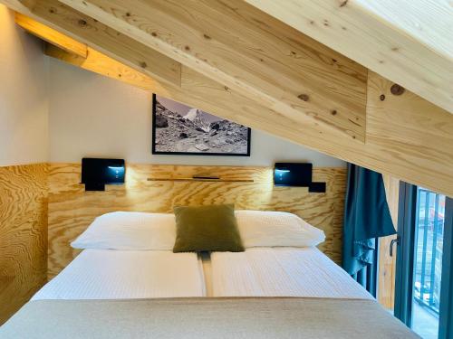 a bedroom with a large white bed with two lights at Peaky Riders Self Check-in Hotel in Zermatt