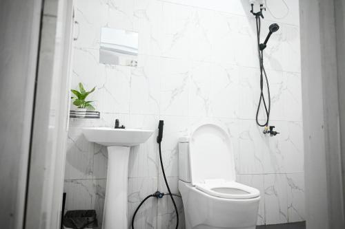 a white bathroom with a toilet and a sink at Fanda Home Syariah in Cimanggu