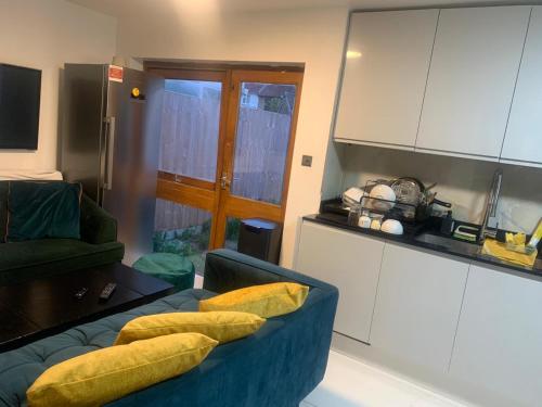 mayfair في Northolt: غرفة معيشة مع أريكة زرقاء مع وسائد صفراء