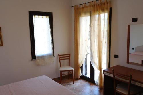 a bedroom with a bed and a desk and a window at Bari Sardo Le More Suite 3 in Bari Sardo