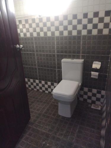 Camera piastrellata dotata di bagno con servizi igienici bianchi. di Precious Home stays a Maragoli