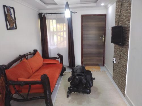 ein Wohnzimmer mit einem orangenen Sofa und einer Kamera in der Unterkunft Precious Home stays in Maragoli