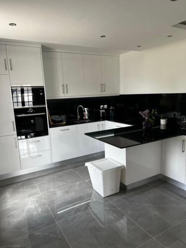 une cuisine avec des armoires blanches et un comptoir noir dans l'établissement Villa near CDG Paris aeroport, à Arnouville-lès-Gonesse