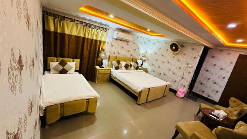 a bedroom with two beds and a chair and a table at Amyl's Garden in Islamabad