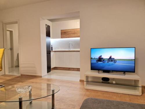 Una sala de estar con un televisor de pantalla plana con dos motocicletas en él. en Novi Apartman NPS Pula, en Pula