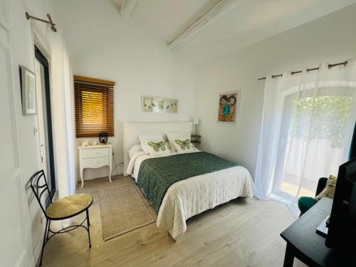 a white bedroom with a bed and a window at LES CISTES in Mallemort