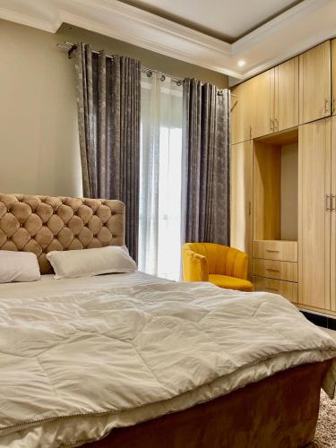 een slaapkamer met een groot bed en een gele stoel bij Sweet home apartment in Namulanda