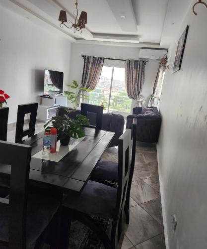 a dining room with a table and chairs and a living room at Magnifique appartement haut standing à Kotto, calme, propre, securise avec groupe electrogene et wifi in Douala