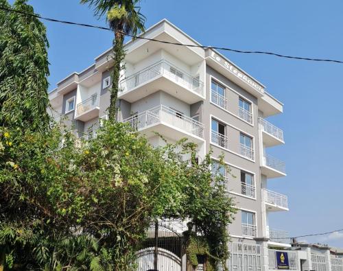 a tall white building with trees in front of it at Magnifique appartement haut standing à Kotto, calme, propre, securise avec groupe electrogene et wifi in Douala