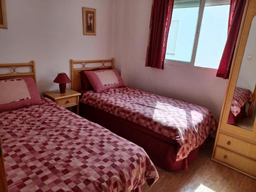 een slaapkamer met twee bedden en een spiegel bij Reina Victoria 2 bed apartment in Rojales