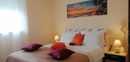 SARITA Apartments 1 في ماكارسكا: غرفة نوم مع سرير مع وسائد ملونة