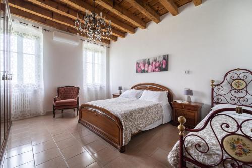 a bedroom with a bed and a chair and a chandelier at Antico Stemma Corte Meneghella in Monzambano