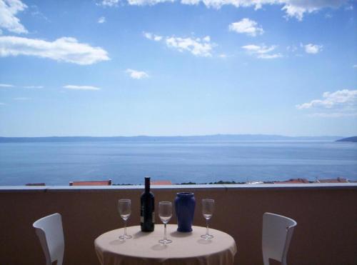 SARITA Apartments 1 في ماكارسكا: طاولة مع زجاجة من النبيذ وكؤوس النبيذ