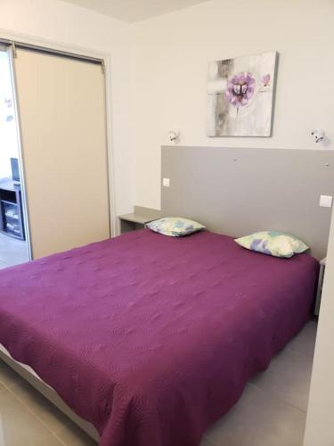 - un lit violet avec deux oreillers dans une chambre dans l'établissement Très joli appartement T2 40 m2 avec piscine, à La Croix-Valmer