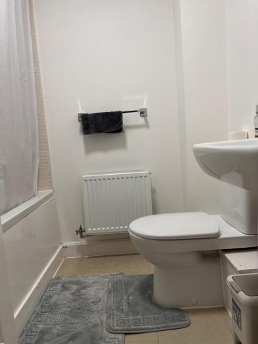 a white bathroom with a toilet and a sink at King-Size Bedroom in Kent