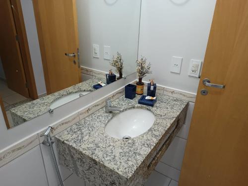 een badkamerbar met een wastafel en een spiegel bij Flat Águas da Serra - com acesso ao rio in Rio Quente