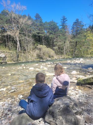 a man and a woman sitting on a rock by a river at chalet gentiane cosy T2 labellisé Dévoluy in Superdevoluy